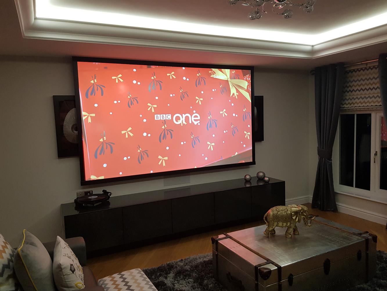 Projector screen coming down in front of TV in living room home theatre