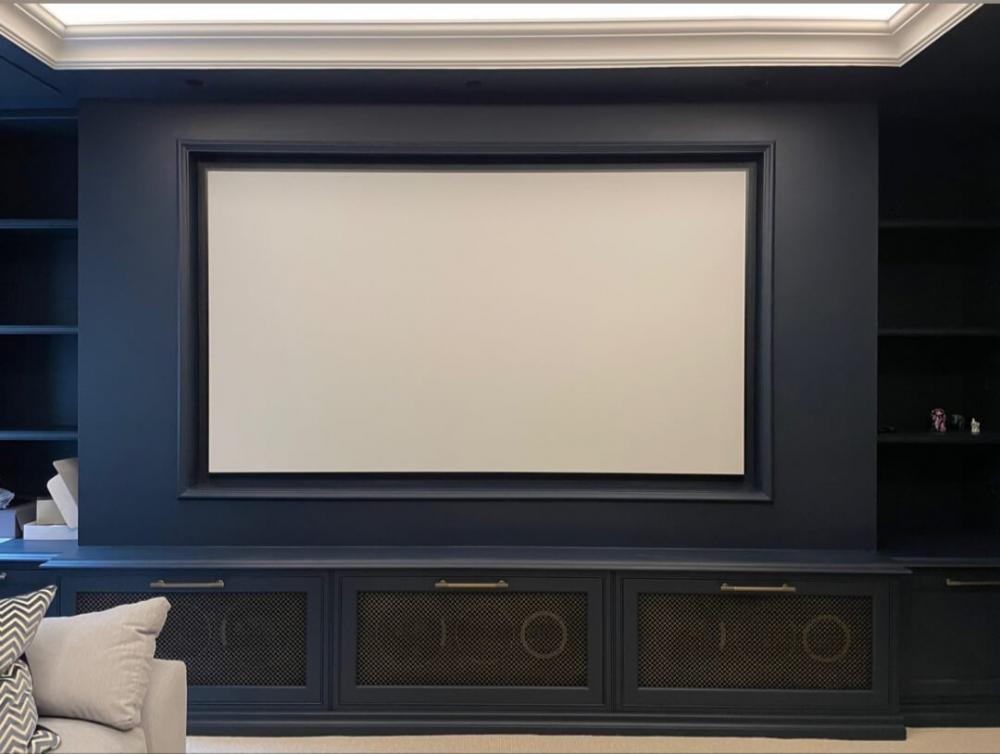 Projector screen built into a media wall with blue walls and cabintry