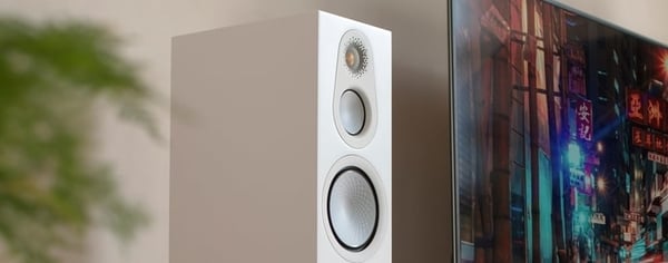 Monitor Audio Silver 300 7G Satin White Floorstanding Speaker beside a TV