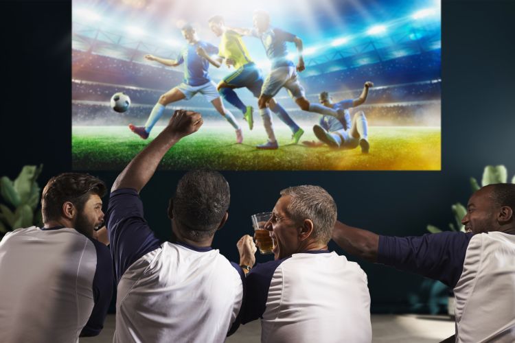 group of men watching football on a projector screen whilst drinking