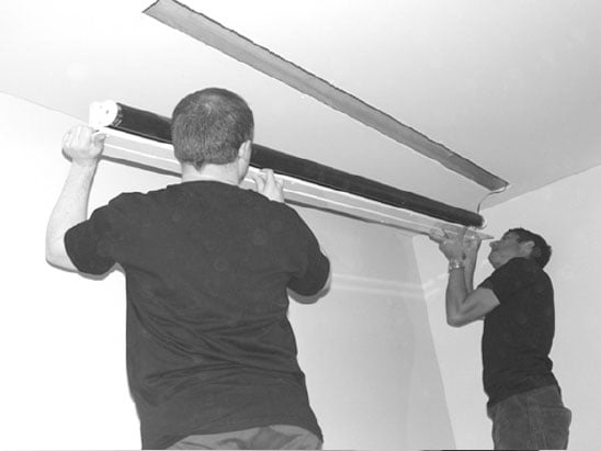 two men lifting projector screen into ceiling
