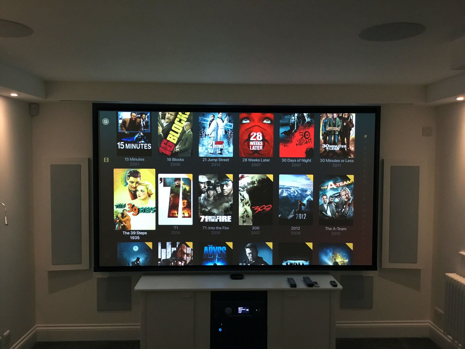 home cinema showing projector screen with speaker either side and cupboard underneath
