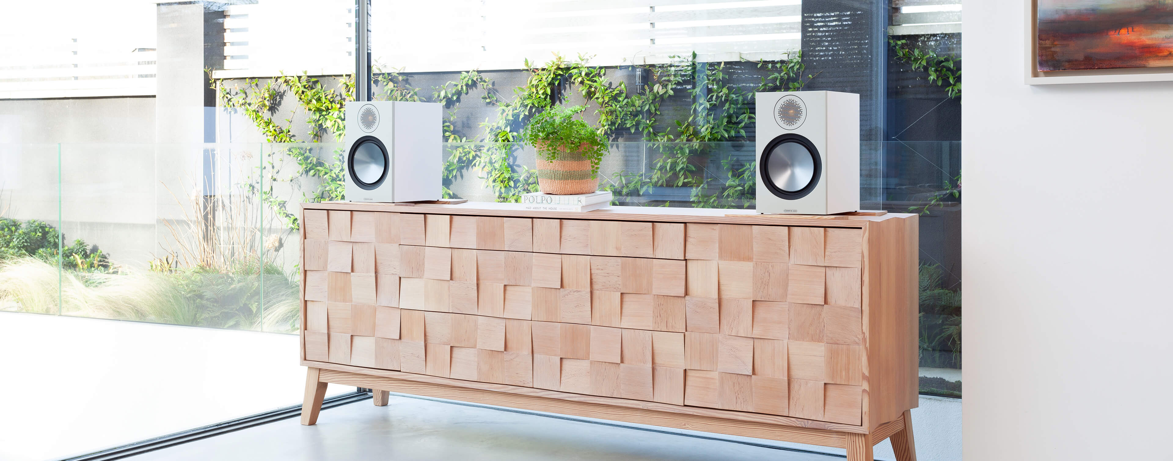 Monitor Audio Bronze 100 Bookshelf Speakers on a cabinet in a living space